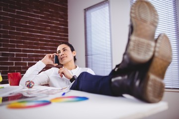 Fototapeta premium Young woman talking on phone in office