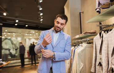 happy young man trying jacket on in clothing store