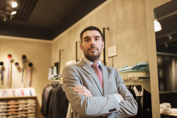 young man or businessman in suit at clothing store