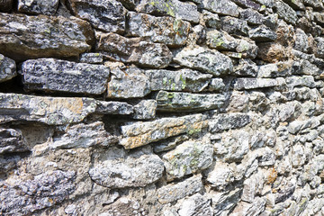 Detail of an old medieval stone wall consumed by time
