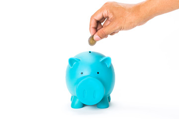 Hand with coin over a blue piggy bank on white background