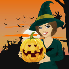 Young woman dressed like witch wearing dark clothing and holding pumpkin in hand