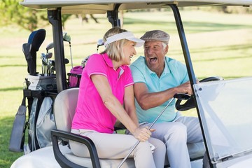 Couple sitting in golf buggy