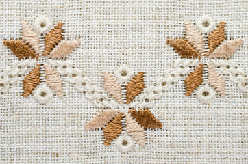 Embroidered fragment on flax by cotton threads. Macro embroidery texture flat stitch.