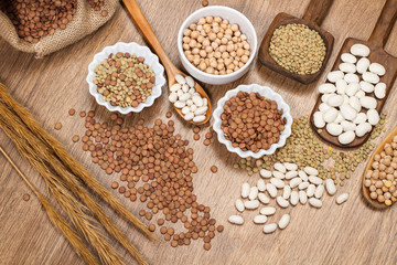 Legumbres naturales y secas sobre una mesa rústica y cucharas de madera. Vista superior