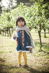 cute little asian girl hold snack package in grape yard, vintage image style