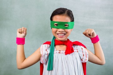 Happy girl dressed as superhero in classroom - obrazy, fototapety, plakaty