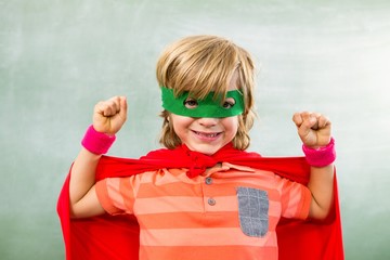 Happy boy dressed as superhero in classroom - obrazy, fototapety, plakaty