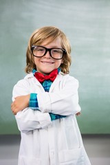 Smiling boy dressed as scientist standing in classroom - obrazy, fototapety, plakaty