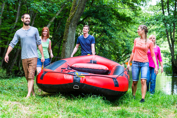 Freunde tragen Schlauchboot zum Wald Fluss 