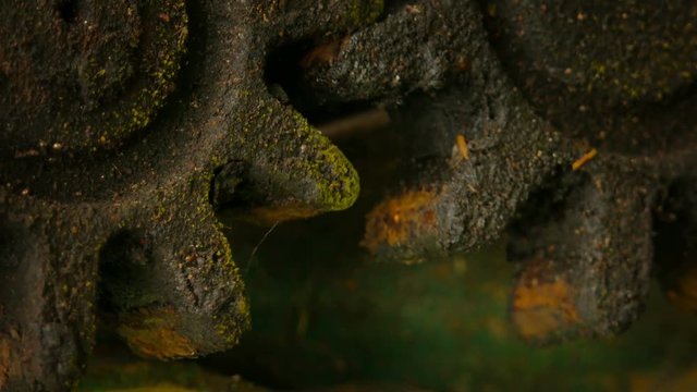Pair of rusty old cogwheels, covered in grease and grime, turning slowly and continuously together. Video 4k