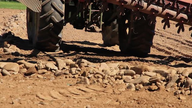 Tractor bajando el rastrillo despedregador para separar o quitar las piedras de la tierra
