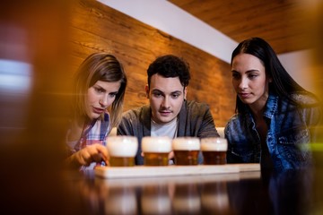 Friends looking at beer glasses on table