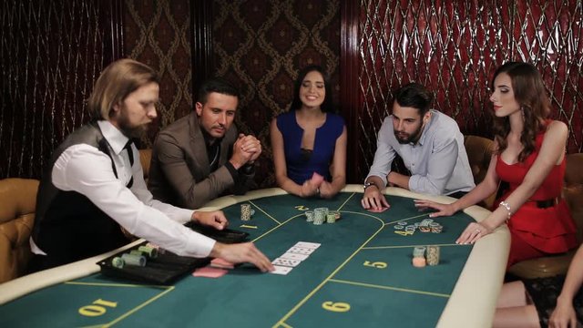 The game of poker. Girl in blue dress enjoys win at the casino.