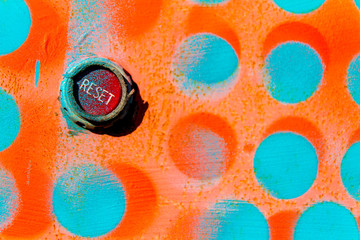 red reset button on wall painted with blue and orange dots - obrazy, fototapety, plakaty