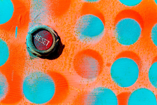 Red Reset Button On Wall Painted With Blue And Orange Dots