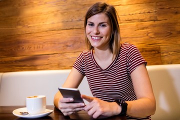 Young woman using cellphone in restaurant