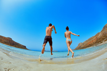 couple running in the sea beach on a blue sky background