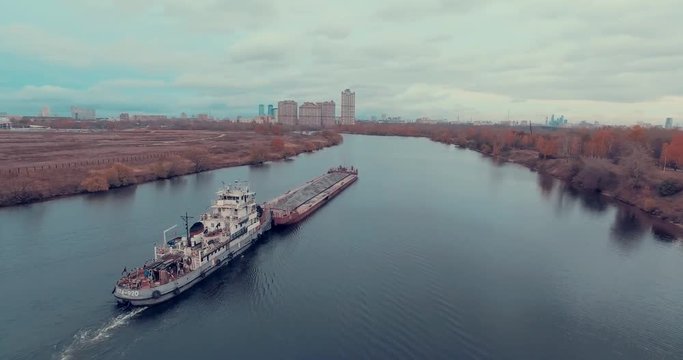 Aerial view of  barge transporting gravel down Moskva River on a cloudy autumn day in Strogino district, Moscow, Russia.  