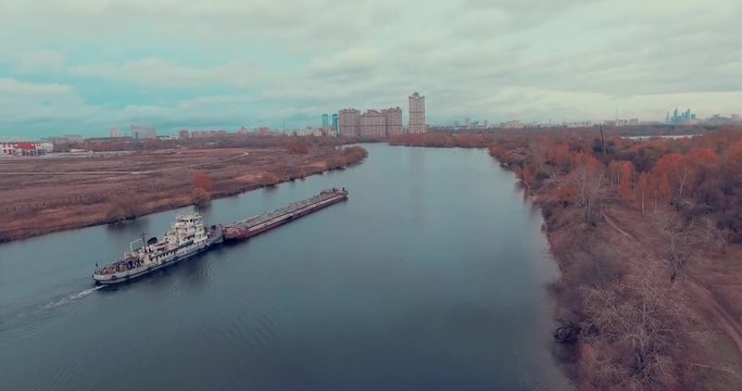 Aerial view of  barge transporting gravel down Moskva River on a cloudy autumn day in Strogino district, Moscow, Russia.  