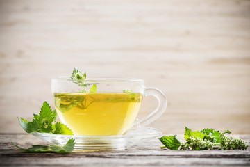 green melissa herbal tea in glass cup on wooden background