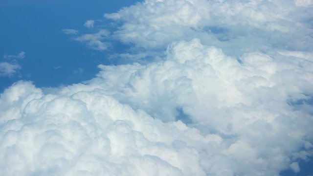 Big, soft, puffy clouds on a bold, blue sky, drifting below, from an airborne perspective. Video UltraHD