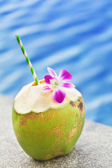 Fresh coconut drink with orchid flower swimming pool