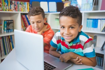 Fototapeta na wymiar School kids using a laptop in library