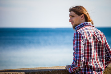 Man long hair relaxing by seaside