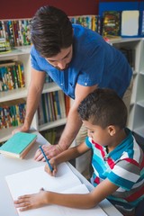 Obraz premium Teacher helping school kid with his homework in library