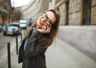 Fototapeta premium Businesswoman walking down the street while talking on smart pho