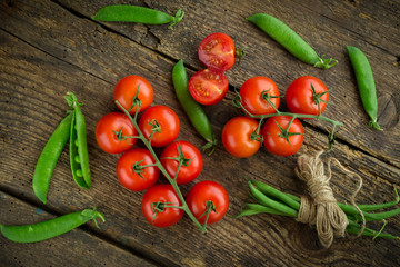 Fresh tomatoes with asparagus and green peas on a wooden backgro