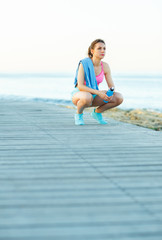 Sunny morning on the beach, athletic woman resting after running