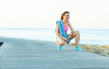 Sunny morning on the beach, athletic woman resting after running