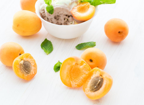 Ice cream with apricots and mint on a white wooden background