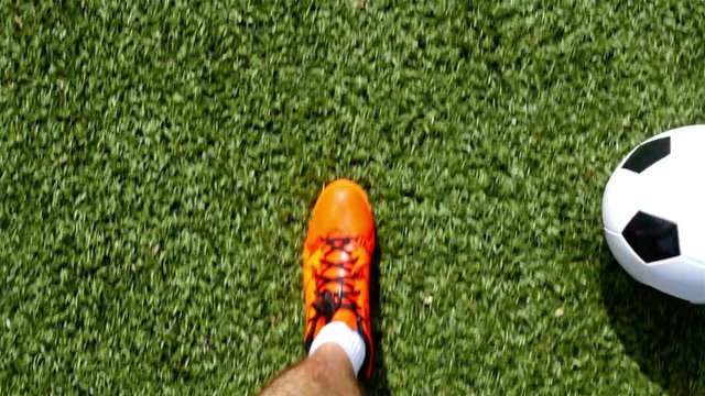 Footballer with orange shoes leading the ball, top view