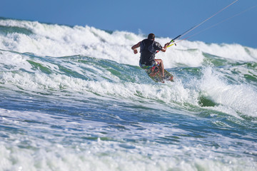 Naklejka premium Athletic man riding on kite surf board sea waves