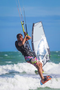 Athletic man riding on kite surf board sea waves