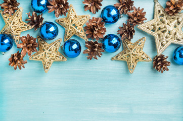 Christmas or new year decoration background: pine cones, blue glass balls, golden stars on painted...