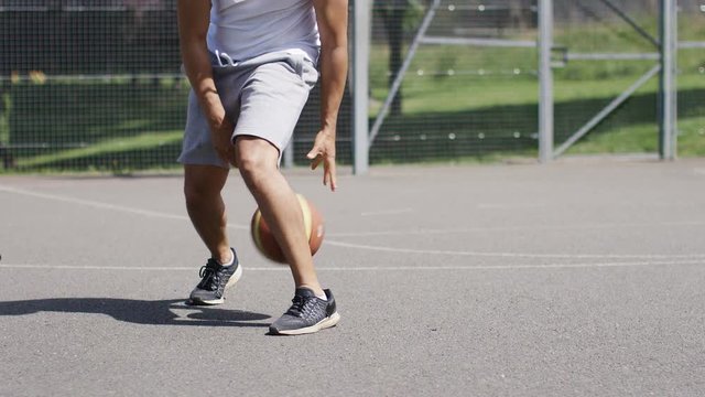 4K Unseen man dribbling a basketball with skill, in slow motion, with space for text