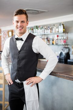 Portrait of waiter standing at bar counter