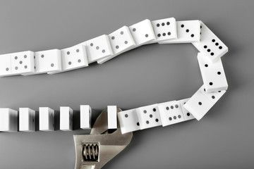 Dominoes with wrench on grey background
