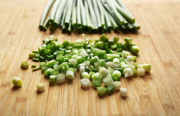 Chopped green onion on wooden cutting board