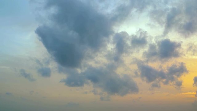 Soft, fluffy clouds in all the colors of the dawn light, drifting slowly across a blue sky. Video 4k
