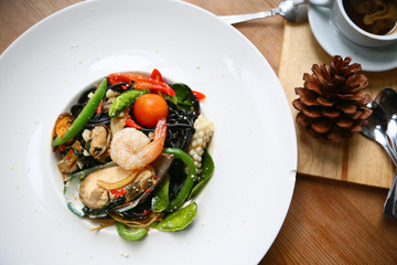 spaghetti with prawns and seafood on white plate, black spaghetti with seafood on table in restaurant, spicy spaghetti in food festival, italian food by spaghetti seafood, international food.