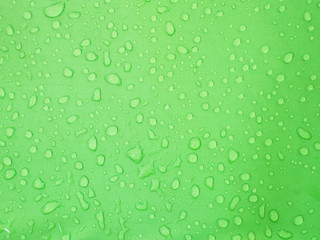 Fototapeta na wymiar water drops on green waterproof fabric