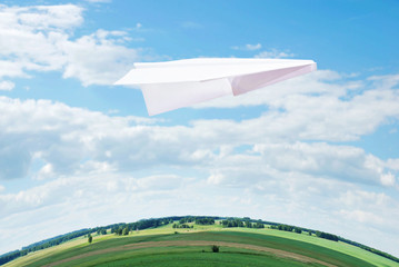 Fototapeta premium Toy paper plane flying high in the sky over the Earth