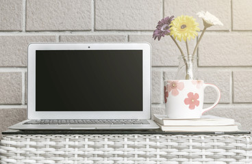 Closeup computer on blurred wood weave table and brown brick wall texture background , beautiful work place interior of house concept