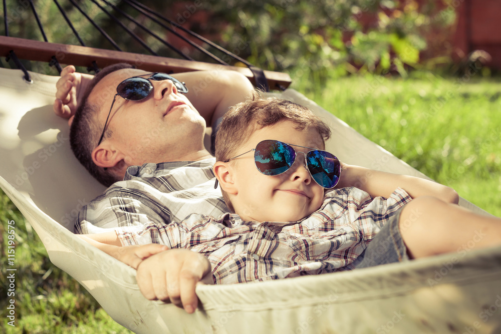 Wall mural father and son lying on hammock in the garden.