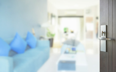 opened wooden door to modern living room interior with blue sofa set